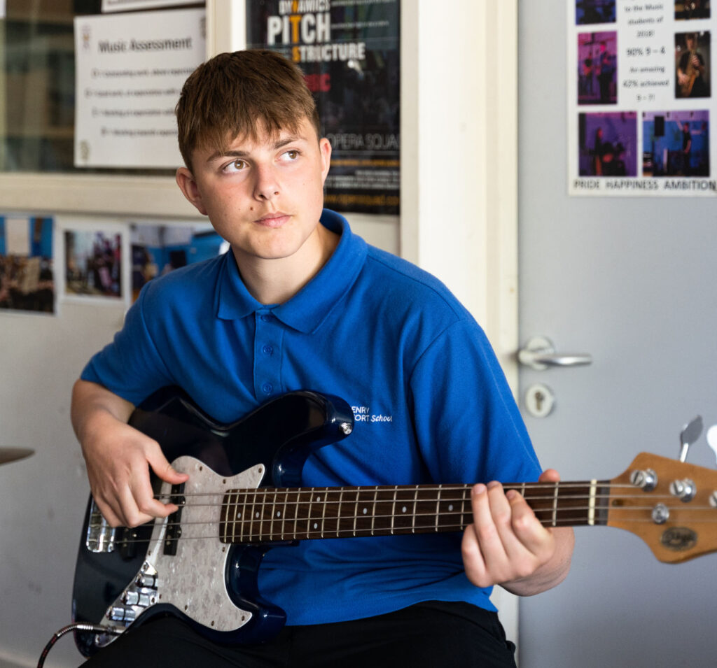 Student playing an electric guitar as part of a music lesson.