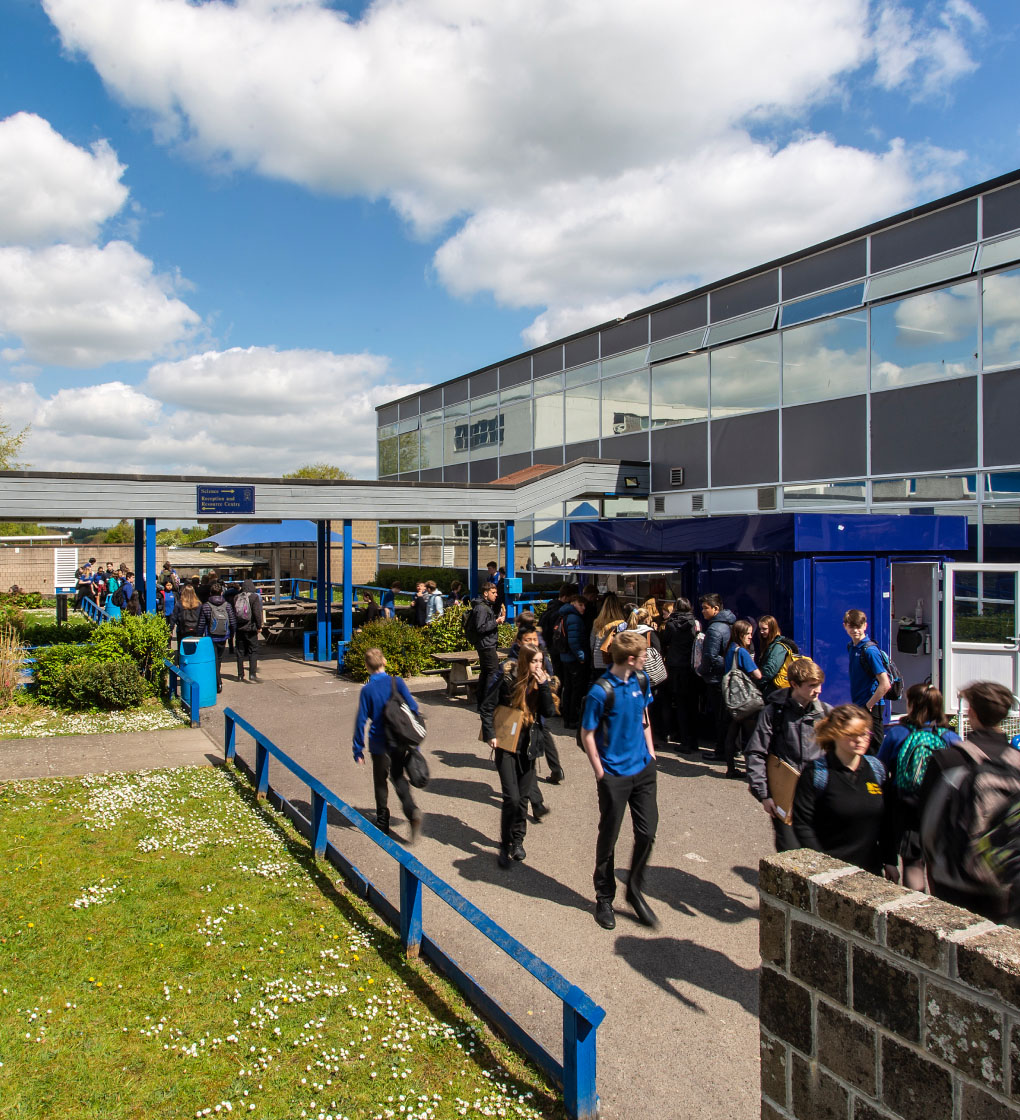 Students walking outside school building, moving between classes during the school day.